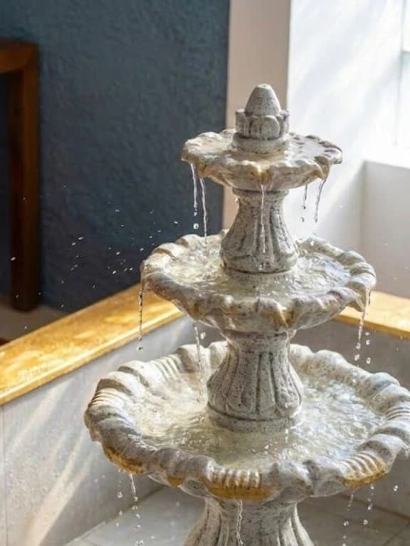 Indoor courtyard fountain at La Maison Pondichéry, with cascading water, arched walkways, and warm evening light