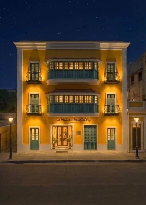 The night façade of La Maison Pondichéry on Rue de Bussy, the yellow heritage house lit against a starry sky
